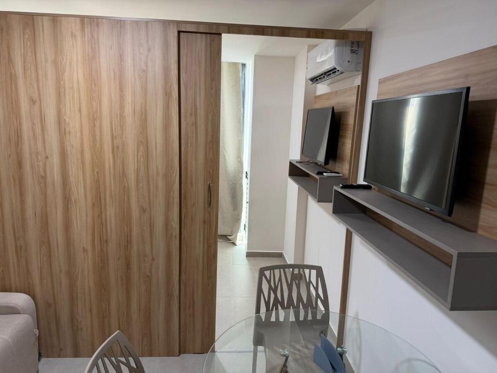 a living room with a glass table and a television at Flat Completo Porto de galinhas in Porto De Galinhas
