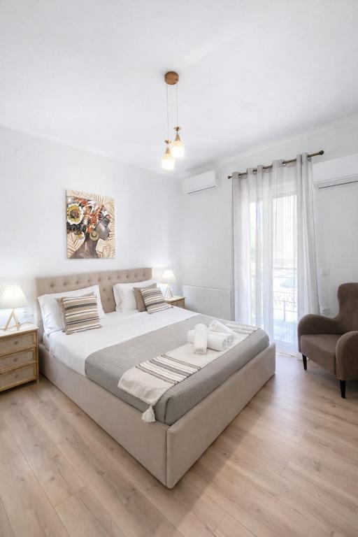 a white bedroom with a large bed and a chair at Liovore Apartments in Lygia
