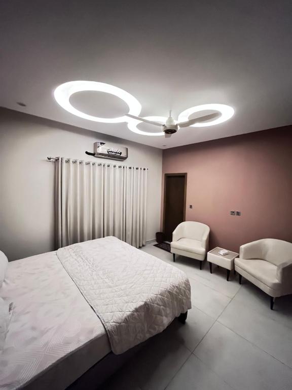 a bedroom with a bed and two chairs and a ceiling fan at Livora stays Cozy Luxury 1BHK in Multan