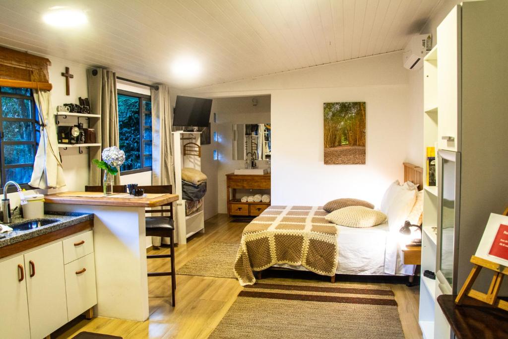 a small kitchen with a bed in a room at Casa do Tecelão - Refúgio, jardim e tranquilidade in Curitiba