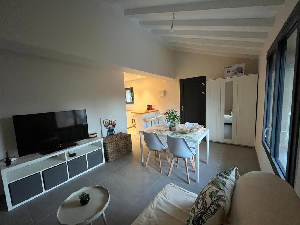 a living room with a couch and a table with chairs at Studio neuf au calme proche Grenoble in Saint-Ismier