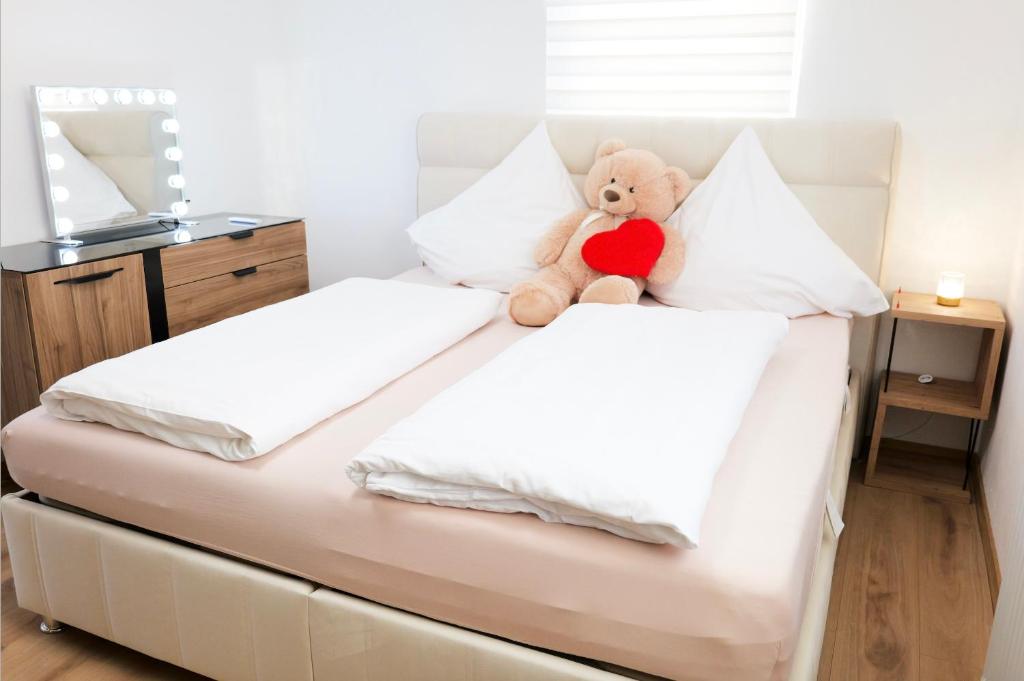 Ein Teddybär sitzt auf einem Bett mit einem Herz in der Unterkunft Bronsliving in Schleiden