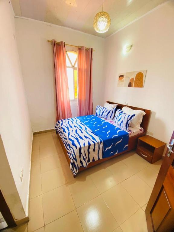 una camera da letto con un letto con piumone blu e una finestra di sidof a Yaoundé
