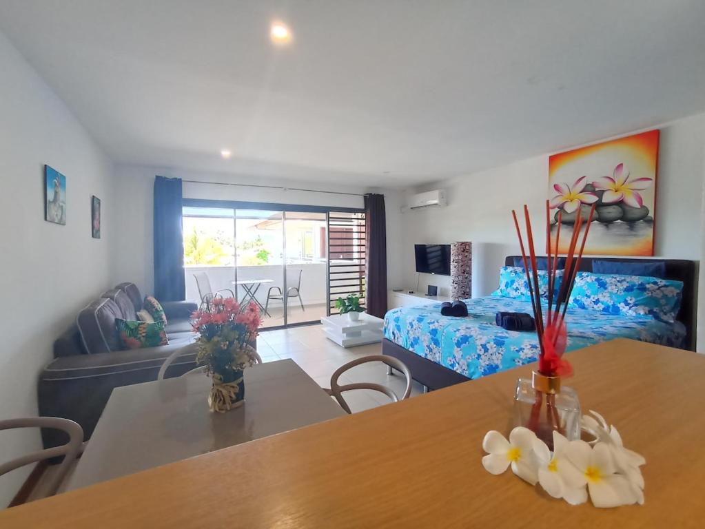 a living room with a bed and a table with flowers on it at Studio Coquet - Mautara Lodge in Bora Bora