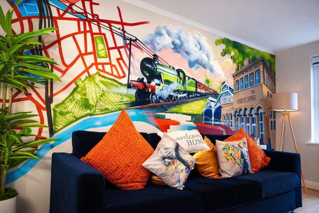 a living room with a blue couch with a train mural at Preston Central in Preston