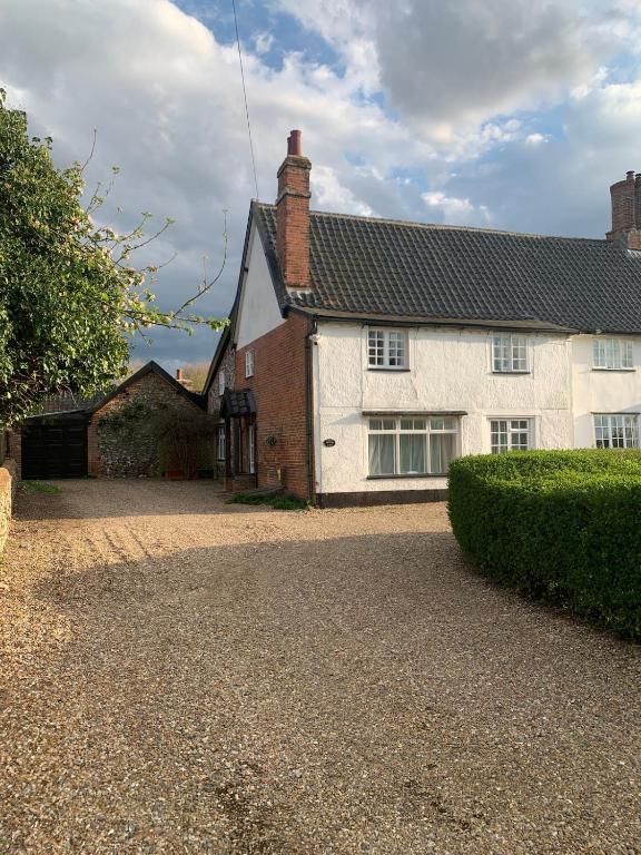 a white house with a driveway in front of it at The Old Stores in Bury Saint Edmunds