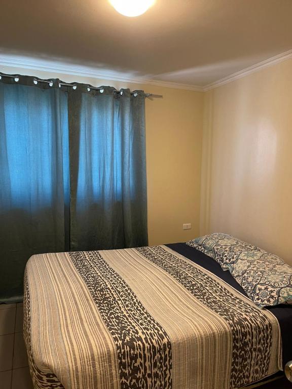 a bedroom with a bed with blue curtains at Apartamentos Lourdes in Antofagasta