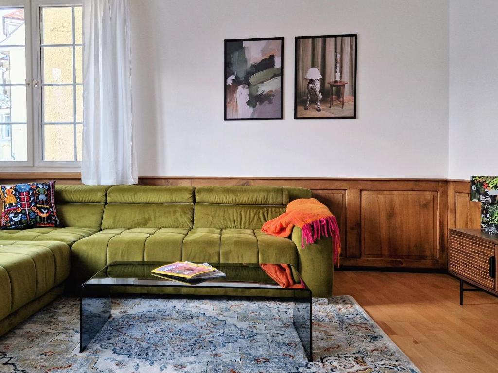 a living room with a green couch and a table at FEWOCASA Central Family Apartment Rorschach - Lake Constance - Near St Gallen in Rorschach