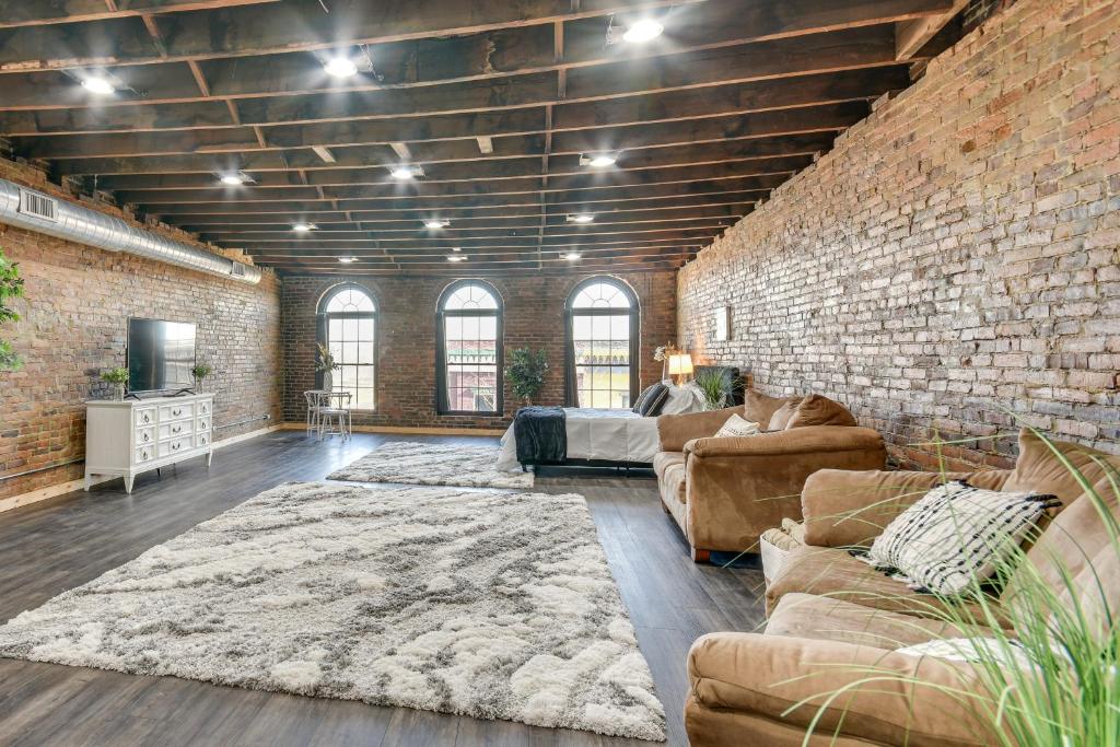 a large living room with a brick wall at Jacuzzi Tub & Full Kitchen: Dowtown Hannibal Loft in Hannibal