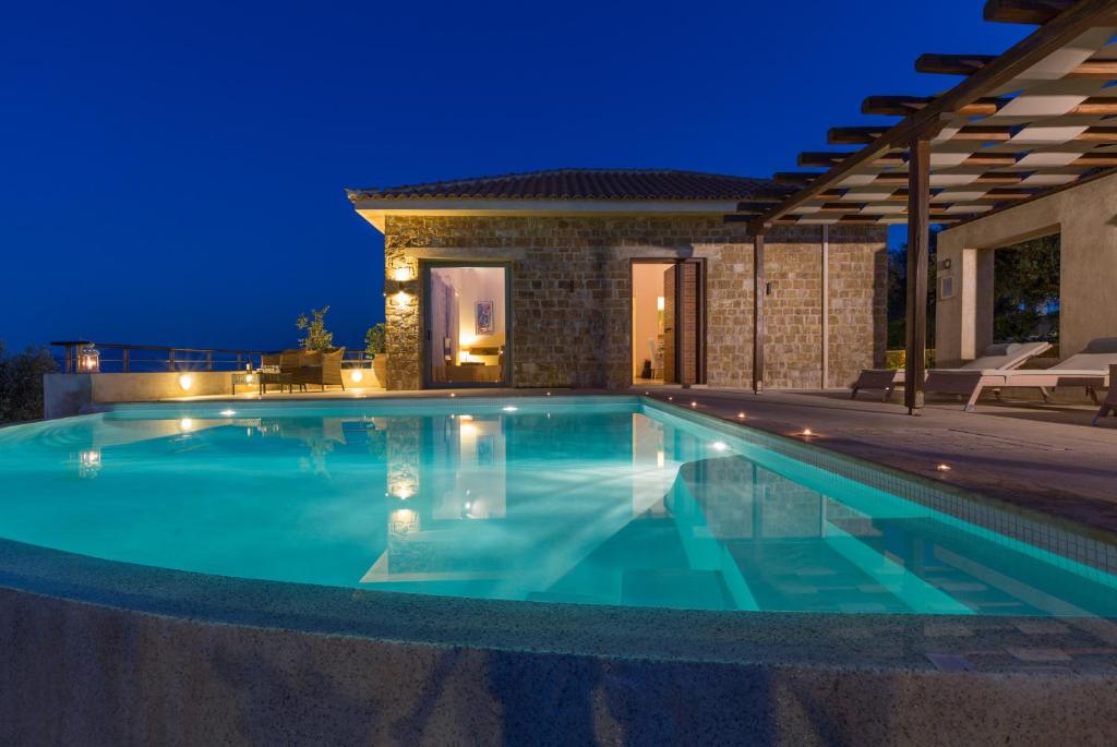 a swimming pool in front of a house at night at Olivia's Villas of Luxury in Skiathos Town