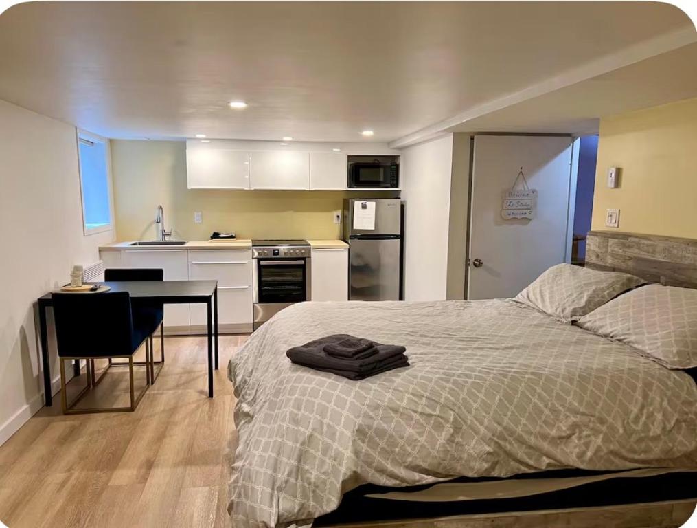 a bedroom with a bed and a table and a kitchen at Studio moderne et tranquille in Montreal