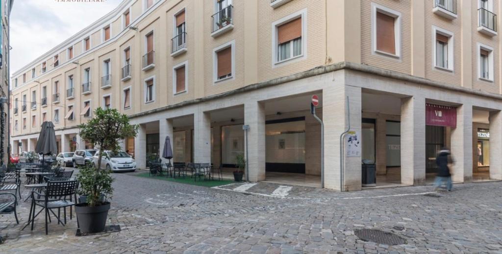 ein großes Gebäude mit Tischen und Stühlen davor in der Unterkunft Rainerio 06 in Fano