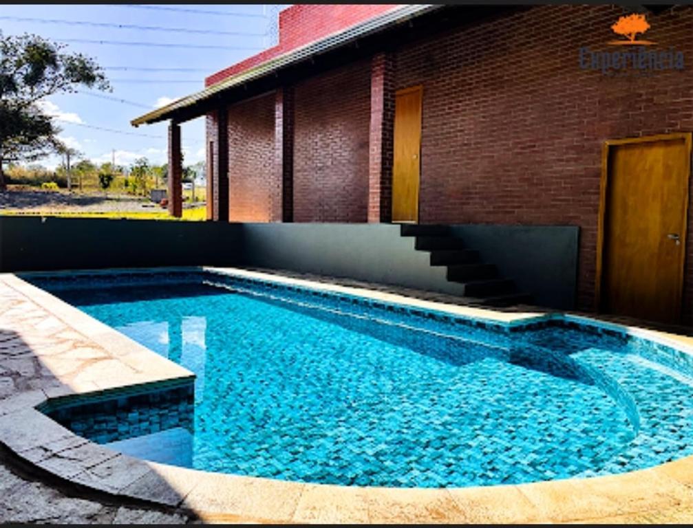 a swimming pool in front of a brick building at Chácara Galileia in Trindade