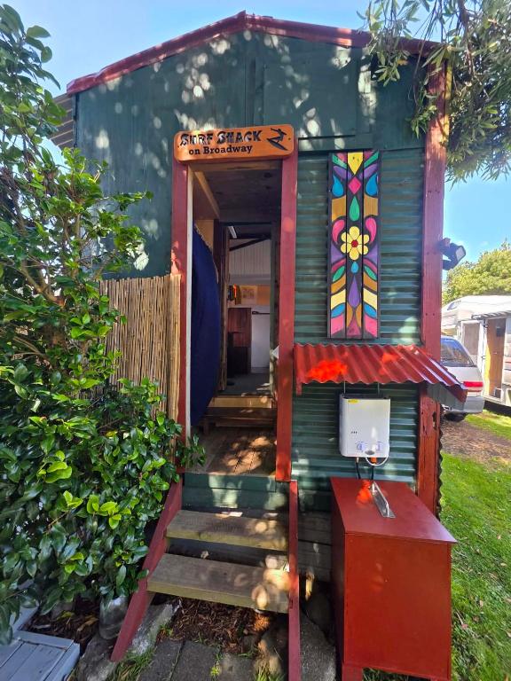 a small house with a door and stairs in a yard at Surf Shack on Broadway in Waitara