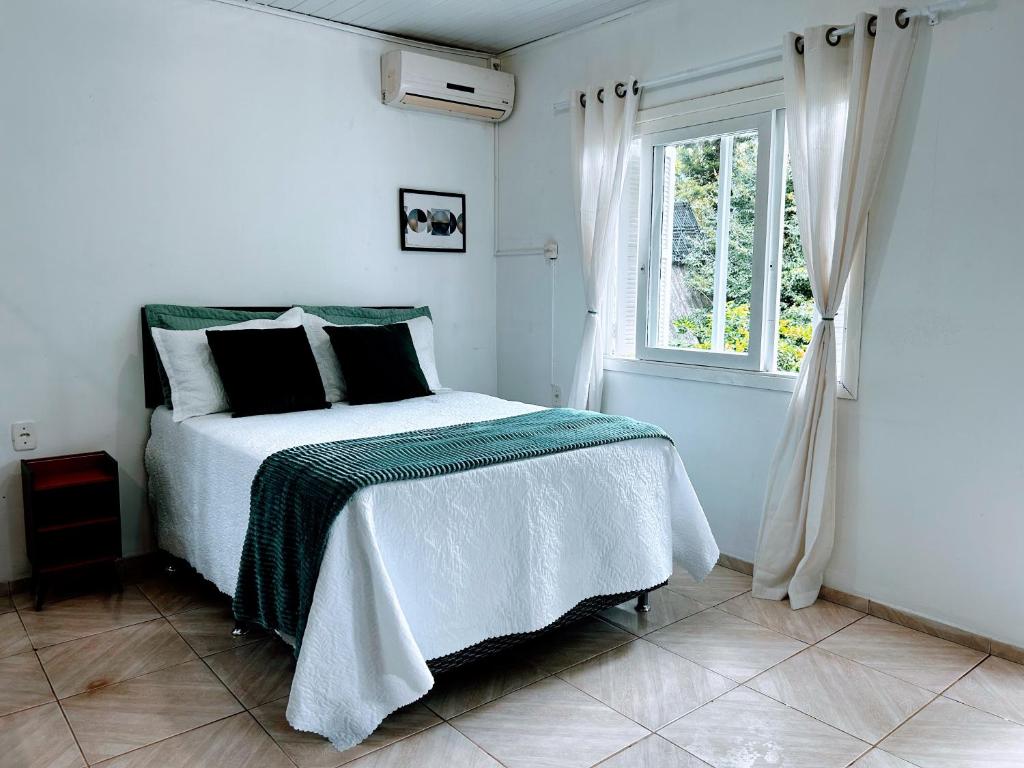 a white bedroom with a bed and a window at Refúgio até 8 pessoas Churrasqueira e pátio cercado in Arroio do Meio