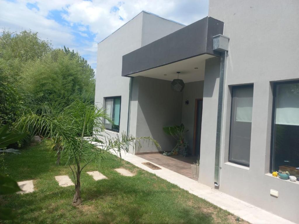 a white house with a palm tree in the yard at Muana Escobar in Belén de Escobar