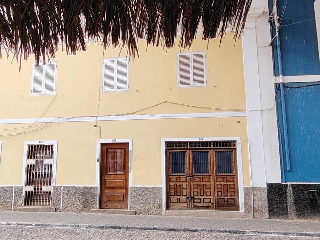 a yellow building with brown doors and windows at Mycoffee Apartment in Mindelo