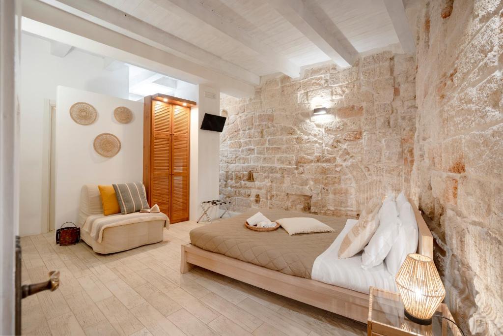 a bedroom with a bed and a stone wall at Old tuff apartments in Polignano a Mare