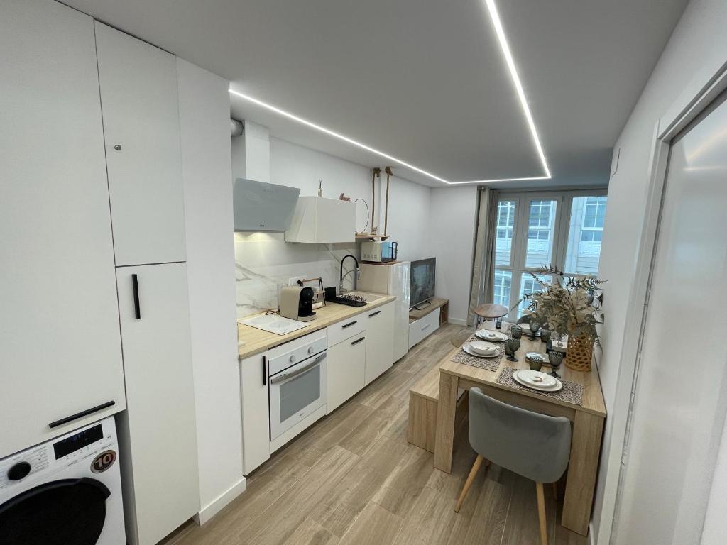 a kitchen with white cabinets and a table with a chair at Pontevedra Apartments -New Loft Centro Pontevedra in Pontevedra