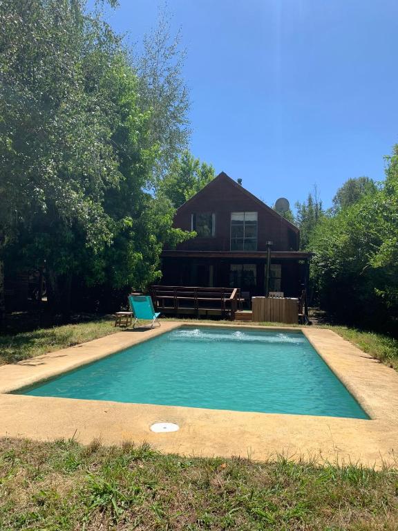 a swimming pool in front of a house at Cabaña Vista Las Bravas in Recinto