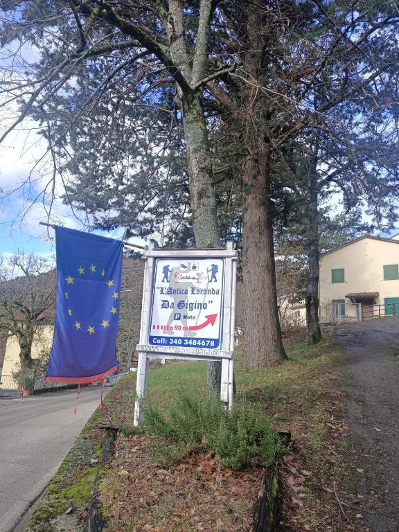 a sign on the side of a road next to a tree at L'Antica Locanda da Gigino in Corniolo