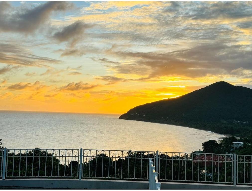 a sunset over a body of water with a mountain at NaboBlue Ocean View Apartment Maunabo PR in Maunabo