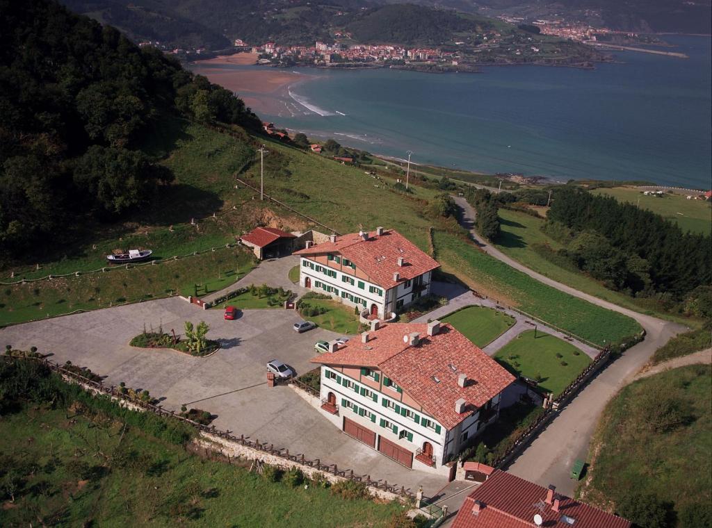 Vue aérienne d'une maison sur une colline à côté de l'eau dans l'établissement Hotel Spa Gametxo, à Ibarrangelu