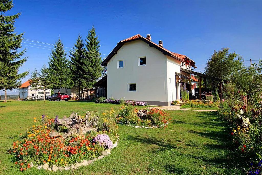 a white house with flowers in a yard at Apartmani Petrović - 3 cozy family apartments in Kaludjerske Bare