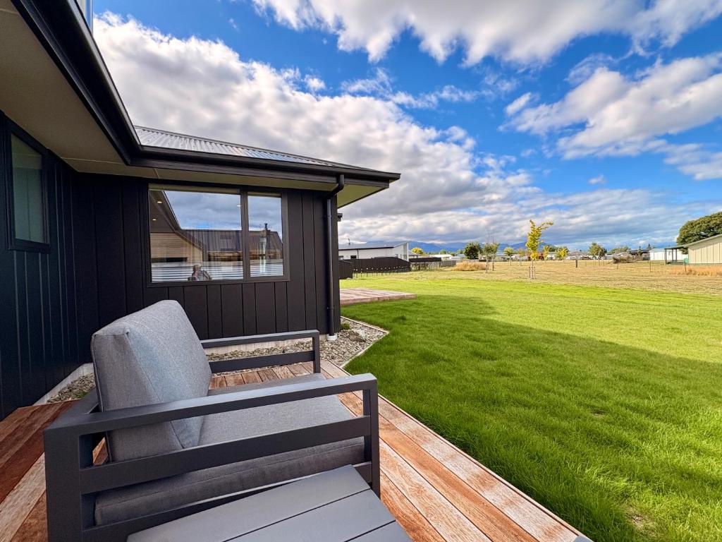 a chair sitting on a deck next to a lawn at Style, Space and Comfort in Twizel