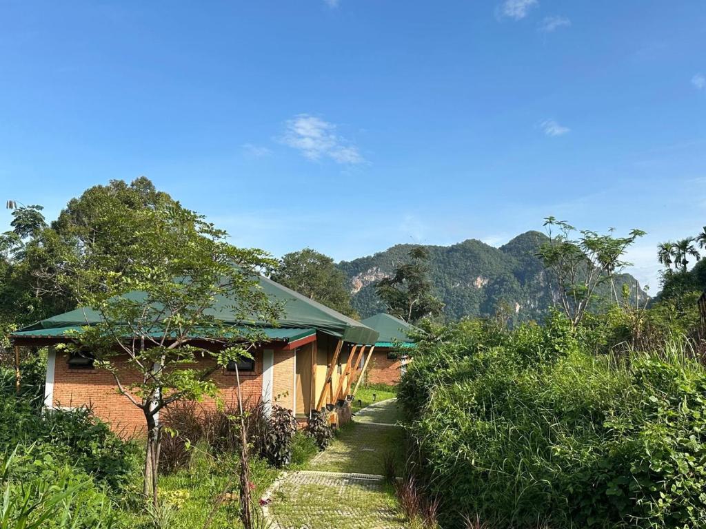 a house in the middle of a field with trees at THANYAWANA Glamping Tents in Khao Sok National Park