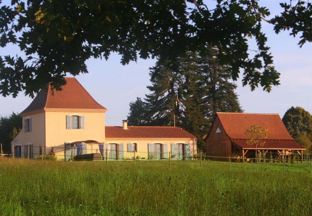 a house and a barn on a grassy field at La Rolandie Haute in Limeuil