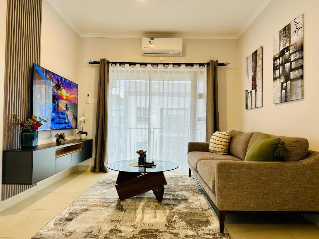 a living room with a couch and a glass table at Moonlight Apartment in Gaborone