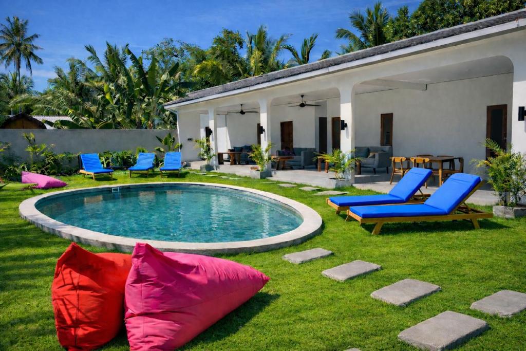 a backyard with a pool and chairs and a house at Wanderlust Hostel - Highest Privacy Hostel In Kuta - Big Clear Pool - Fast Internet in Kuta Lombok