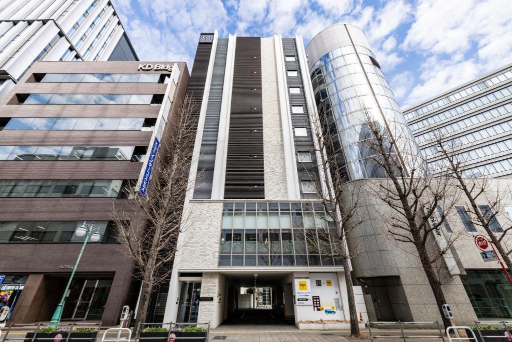 a tall building in a city with trees in front of it at KOKO HOTEL Hakata Shinkansenguchi in Fukuoka