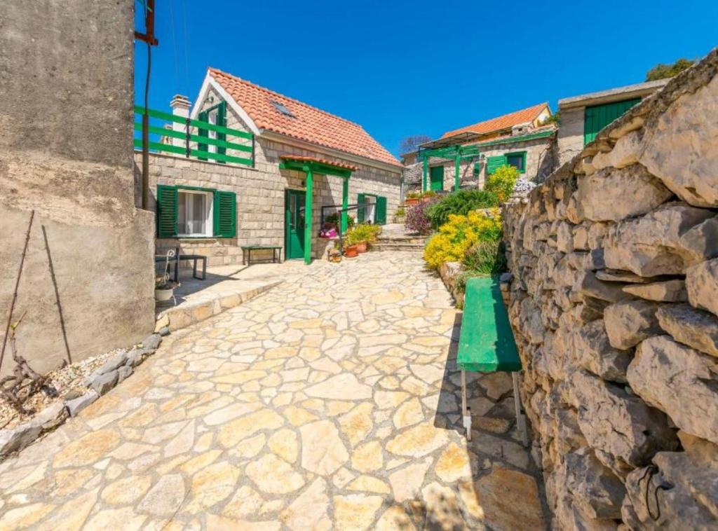 a stone alley with houses and a stone wall at Holiday home Kuzmino in Primošten