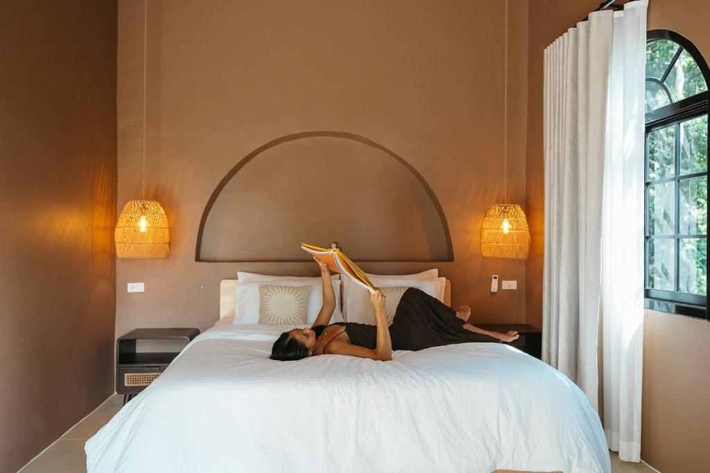 a woman laying on a bed with her legs in the air at Botanica Villas Koh Chang by Indie Beach in Ban Khlong Kloi