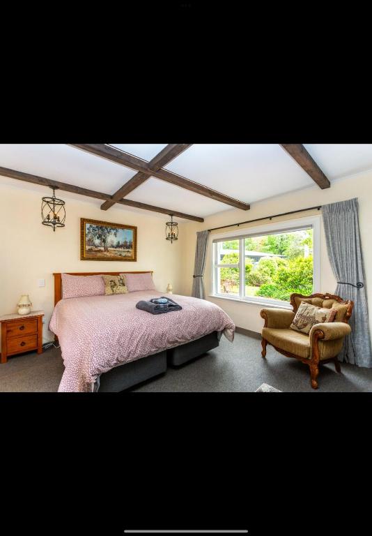 a bedroom with a bed and a chair and a window at The old shearers quarters in Glentunnel