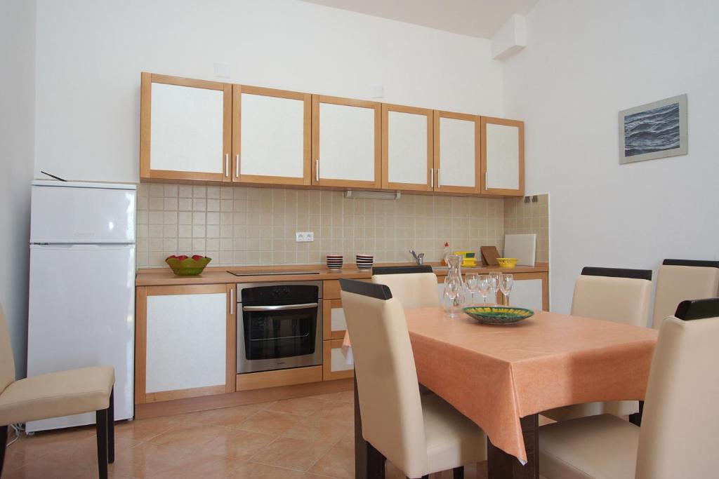 Il comprend une cuisine équipée d'une table en bois et d'un réfrigérateur blanc. dans l'établissement Apartments Novalja, à Novalja