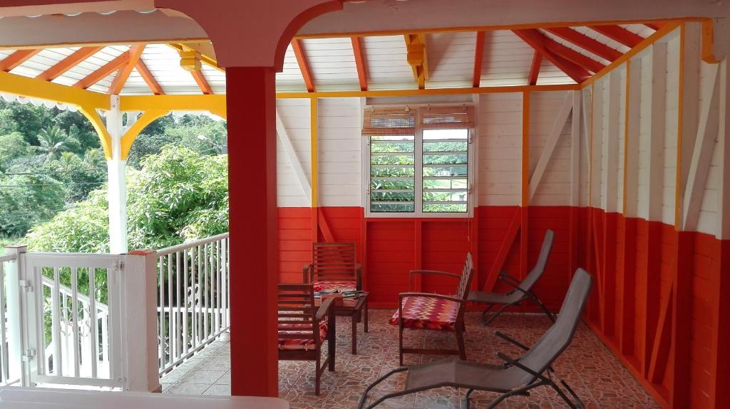 a room with red and white walls and chairs on a porch at Gîte Acélie in Morne-à-lʼEau