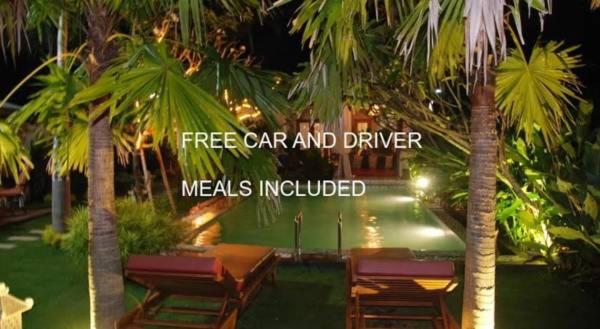 a restaurant with tables and chairs and palm trees at Rosseno Villa in Yogyakarta