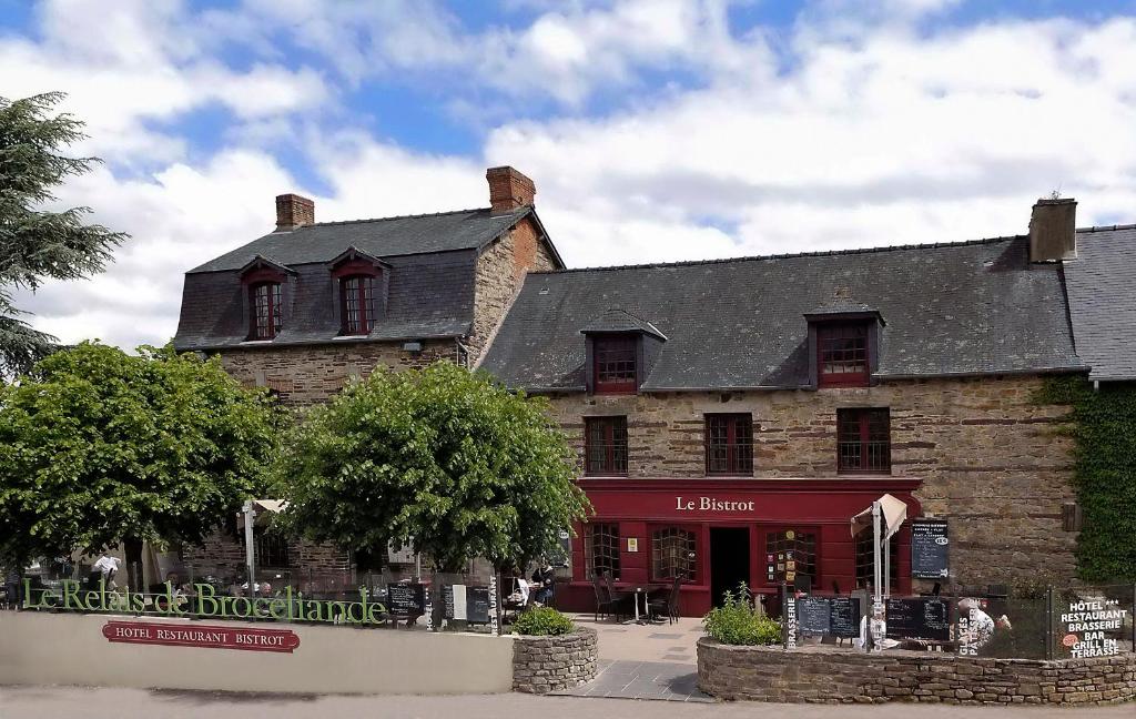 a large brick building with a clock on the front of it at Logis Hotel, restaurant et spa Le Relais De Broceliande in Paimpont