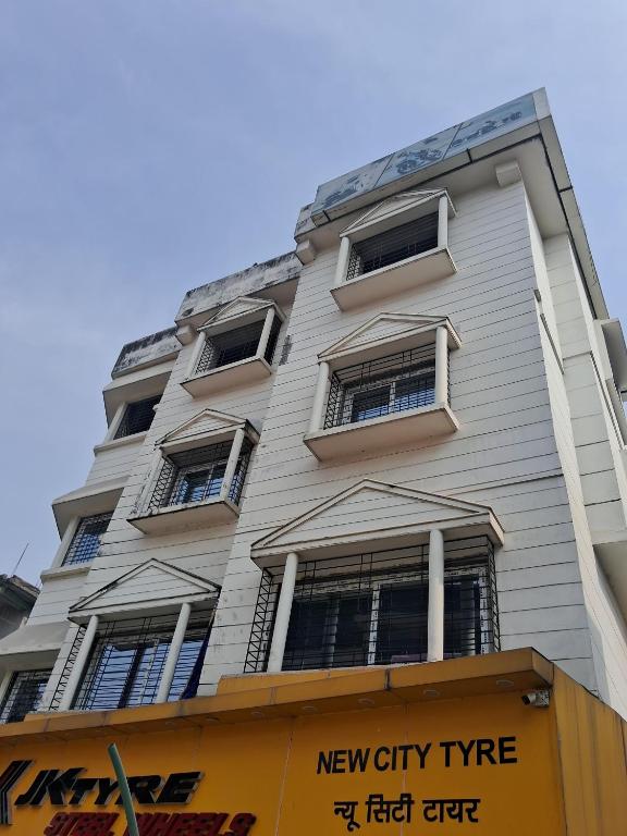 a tall white building with windows and a yellow sign at Sun Hill Homestay in Siliguri