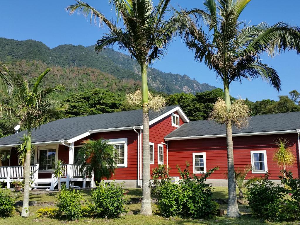 a red house with palm trees in front of it at Hana Mana in Yakushima