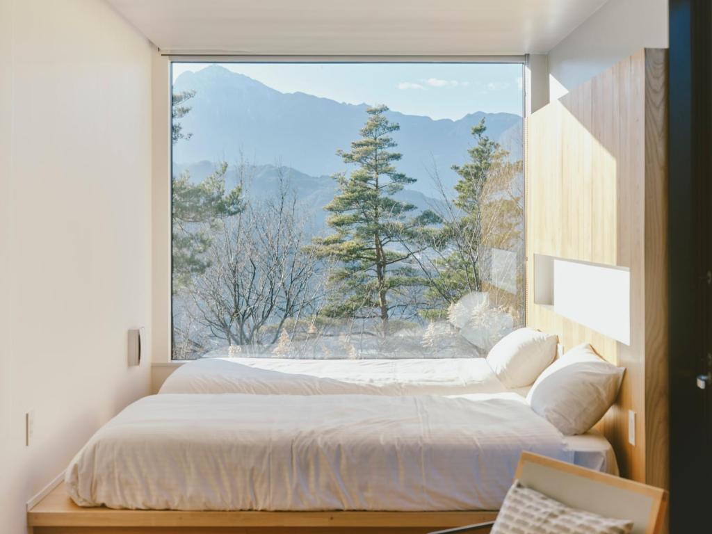 a bedroom with a bed and a large window at BLANC yatsugatake 2026年4月24日グランドオープン in Hokuto