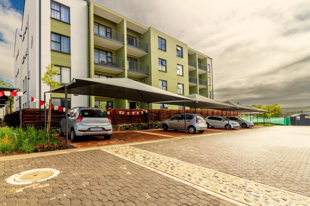 a parking lot with cars parked in front of a building at #Alimama Spaces The Future at Greenlee in Sandton