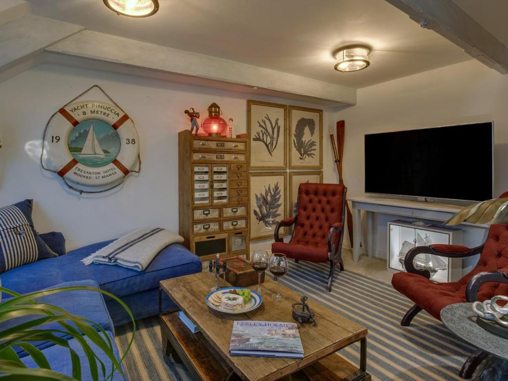 a living room with a blue couch and a tv at The Salt Loft in Fowey