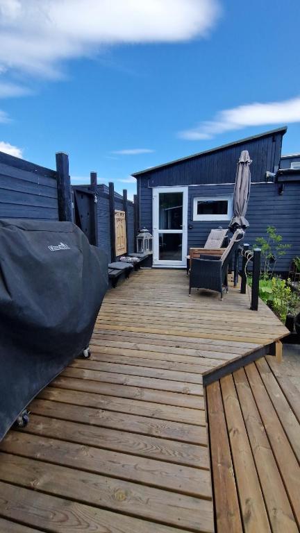 a wooden deck with a chair and an umbrella at Nalle's in Stavtrup