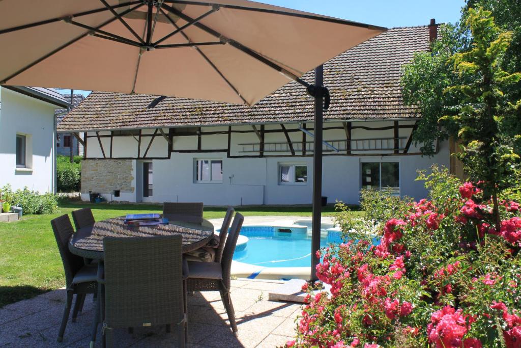 uma mesa com um guarda-chuva ao lado de uma piscina em Le Clos Saint Morand em Balschwiller