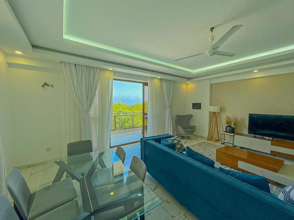 a living room with a blue couch and a glass table at Aqua kingstone apartments in Mombasa