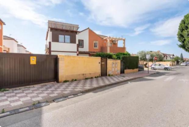 an empty street with a fence and a house at Soluna Alcala in Alcalá del Río